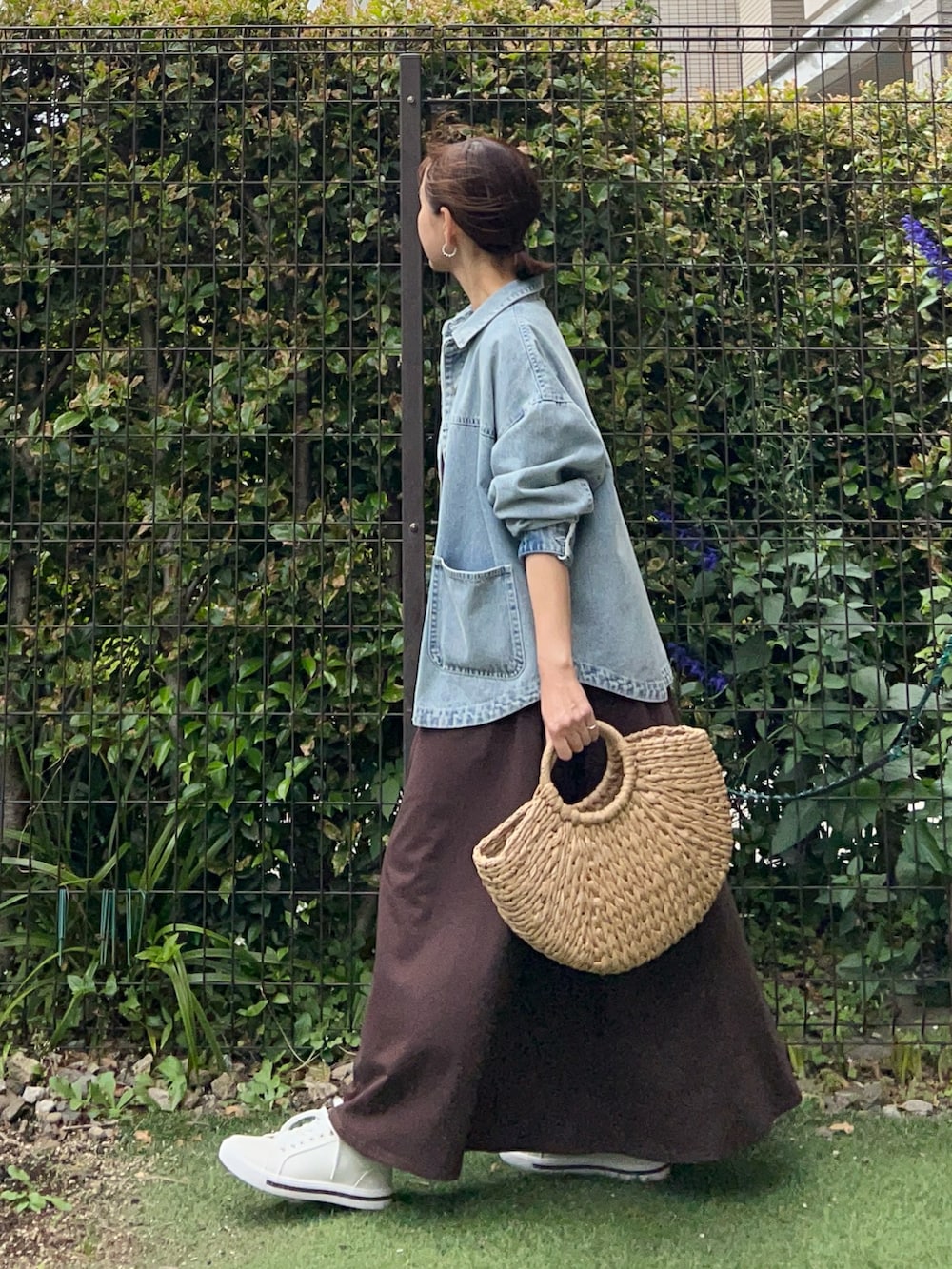 ブルー系のデニムジャケット、ブラウン系のワンピース、ベージュ系のかごバッグを着用したレディースの夏コーディネートの2枚目の写真