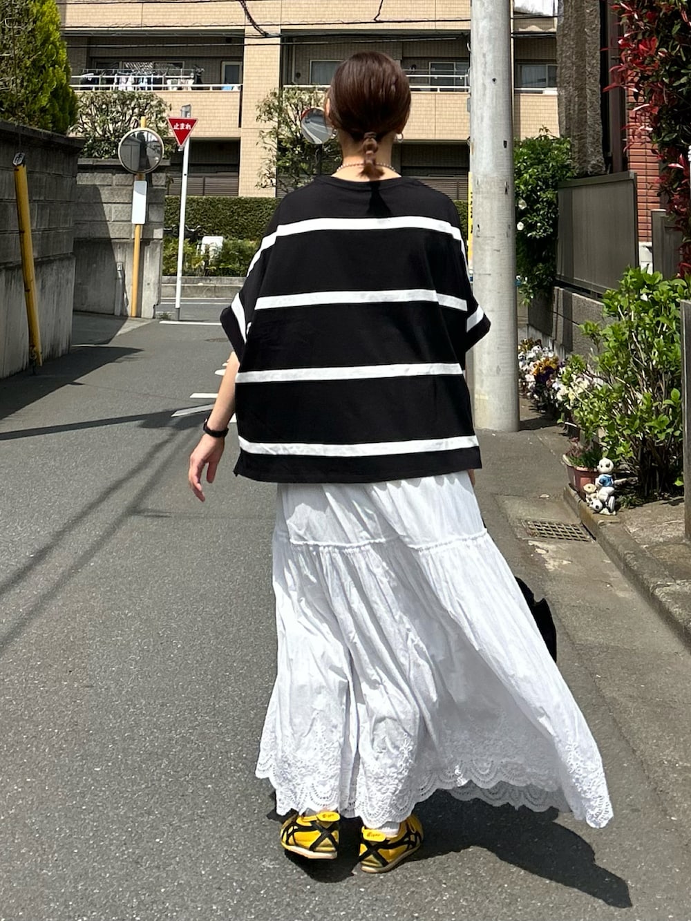 ブラック系のTシャツ/カットソー、ホワイト系のスカート、ブラック系のショルダーバッグを着用したレディースの春コーディネートの4枚目の写真