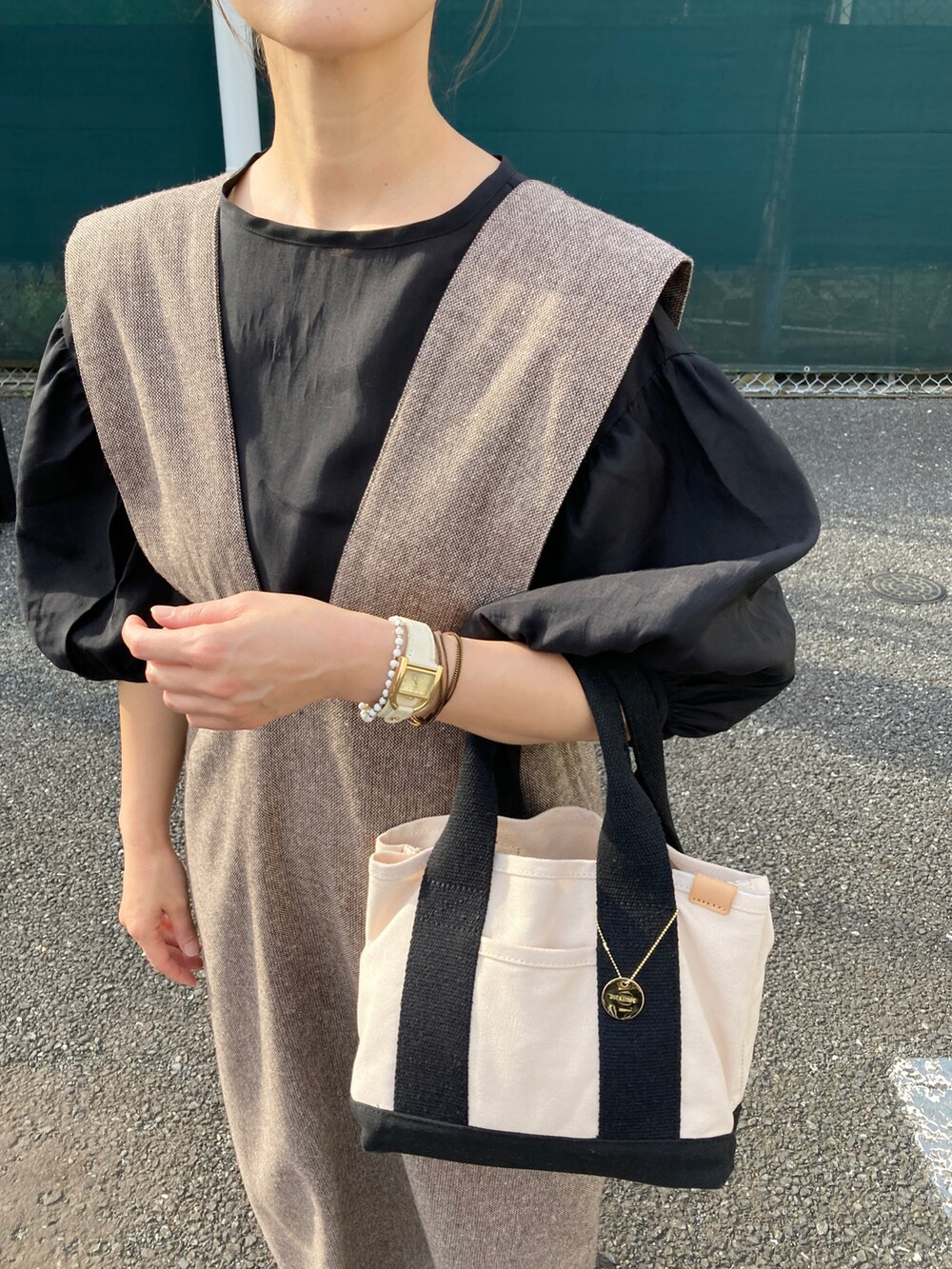ブラック系のシャツ/ブラウス、ブラウン系のジャンパースカート、ホワイト系のトートバッグを着用したレディースの夏コーディネートの3枚目の写真