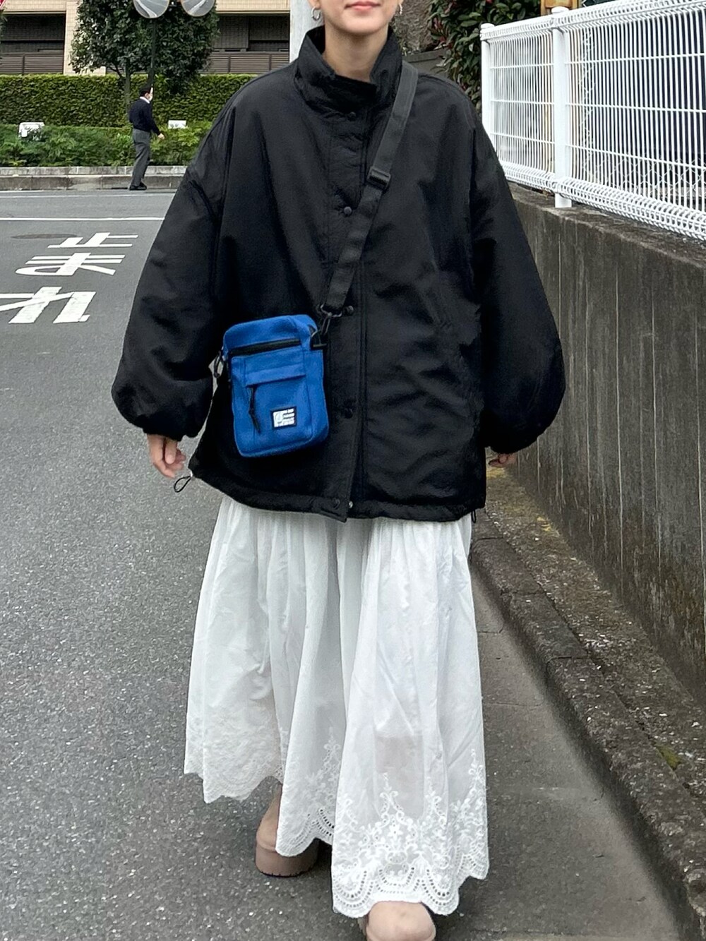 ブラック系のブルゾン、ベージュ系のブーツ、ホワイト系のスカートを着用したレディースの秋コーディネートの5枚目の写真