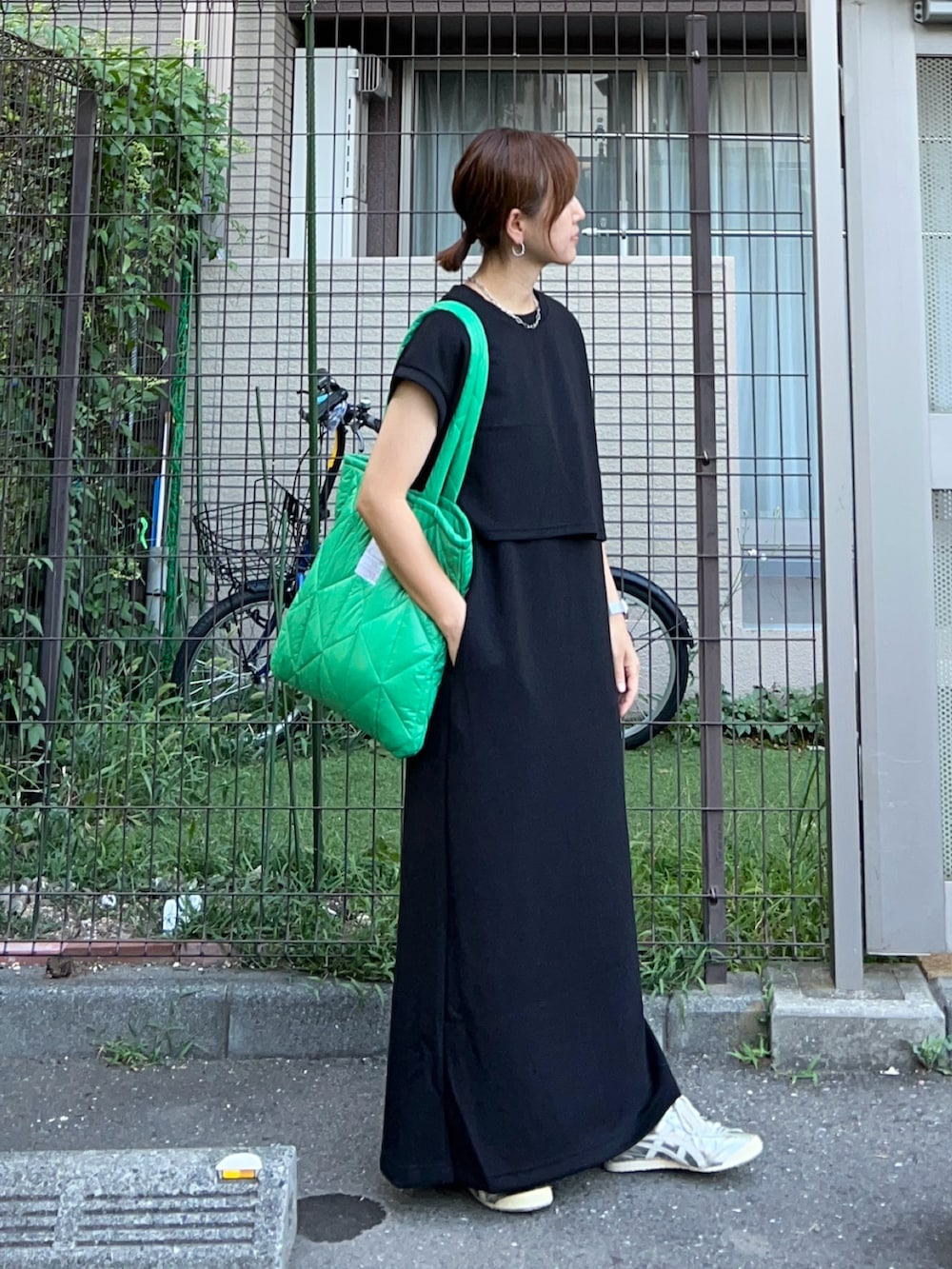 ブラック系のジャンパースカート、グリーン系のトートバッグ、シルバー系のスニーカーを着用したレディースの夏コーディネートの2枚目の写真