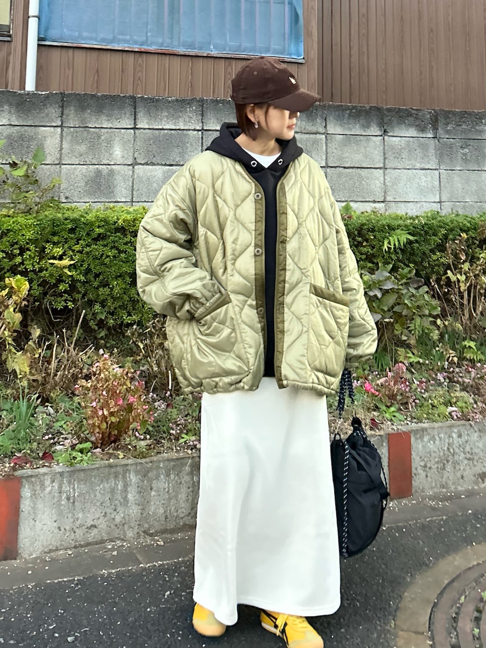 ブラック系のパーカー、ホワイト系のスカート、ブラック系のトートバッグを着用したレディースの冬コーディネートの4枚目の写真