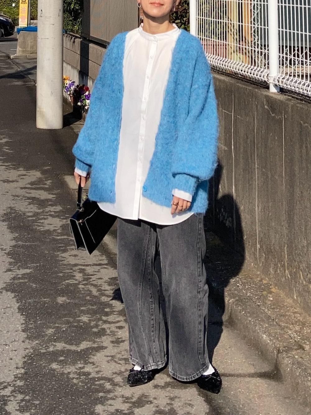 ブルー系のカーディガン/ボレロ、ホワイト系のシャツ/ブラウス、ブラック系のデニムパンツを着用したレディースの冬コーディネートの3枚目の写真