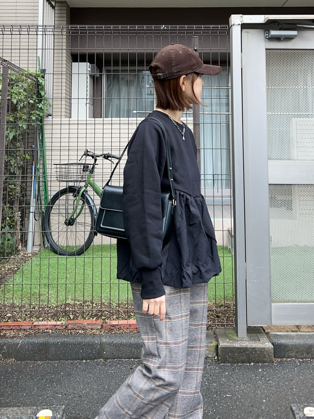 ブラック系のスウェット、ブラック系のハンドバッグ、ブラウン系のキャップを着用したレディースの秋コーディネートの3枚目の写真