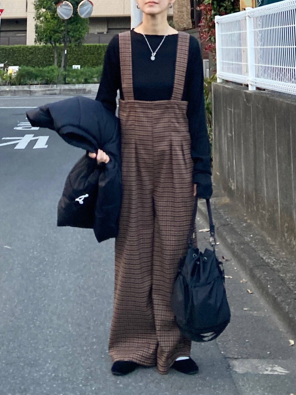 ブラック系のダウンベスト、ブラック系のTシャツ/カットソー、ブラック系のショルダーバッグを着用したレディースの秋コーディネートの3枚目の写真