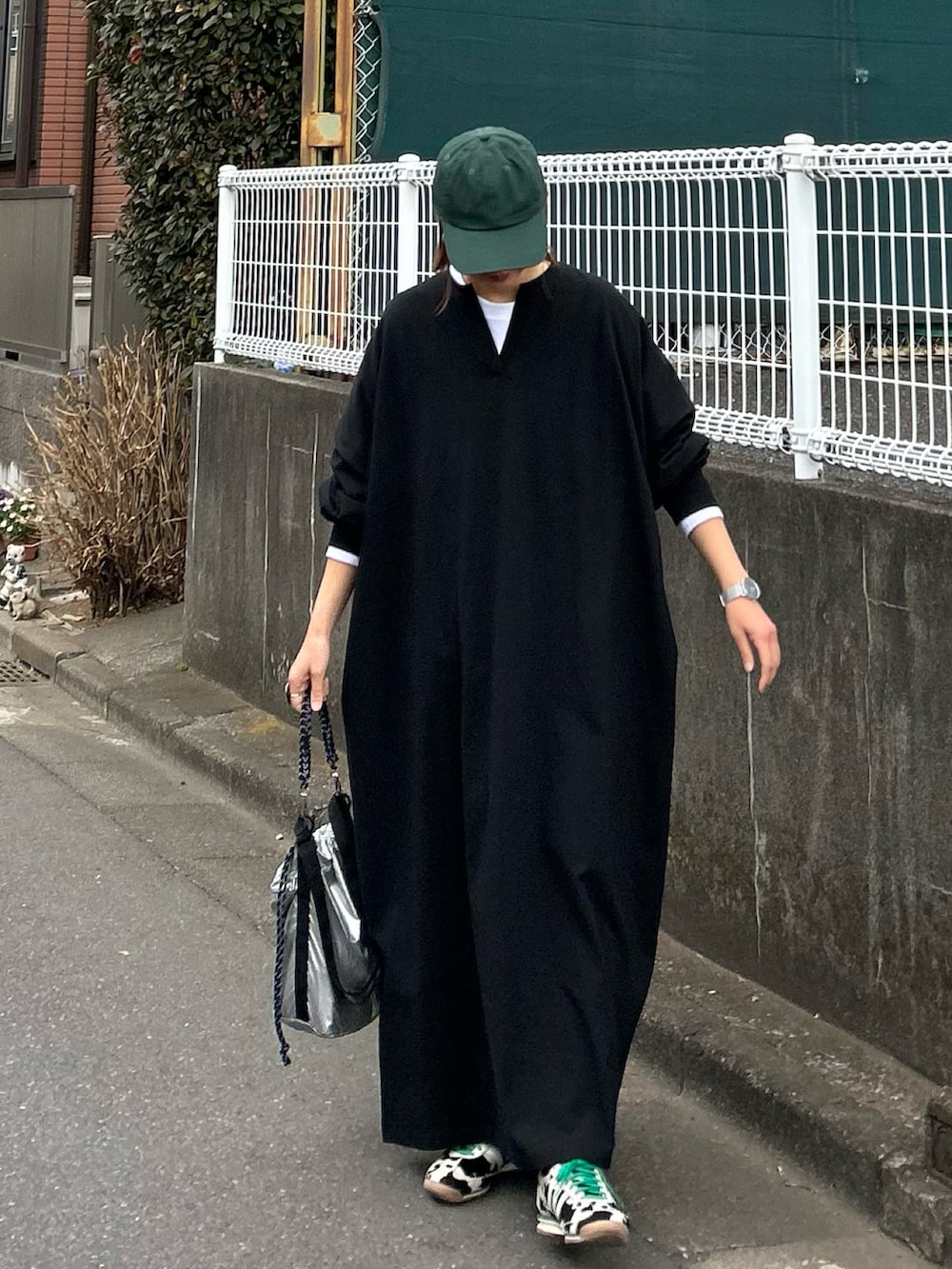 ブラック系のワンピース、シルバー系のトートバッグ、ブラック系のスニーカーを着用したレディースの冬コーディネートの3枚目の写真