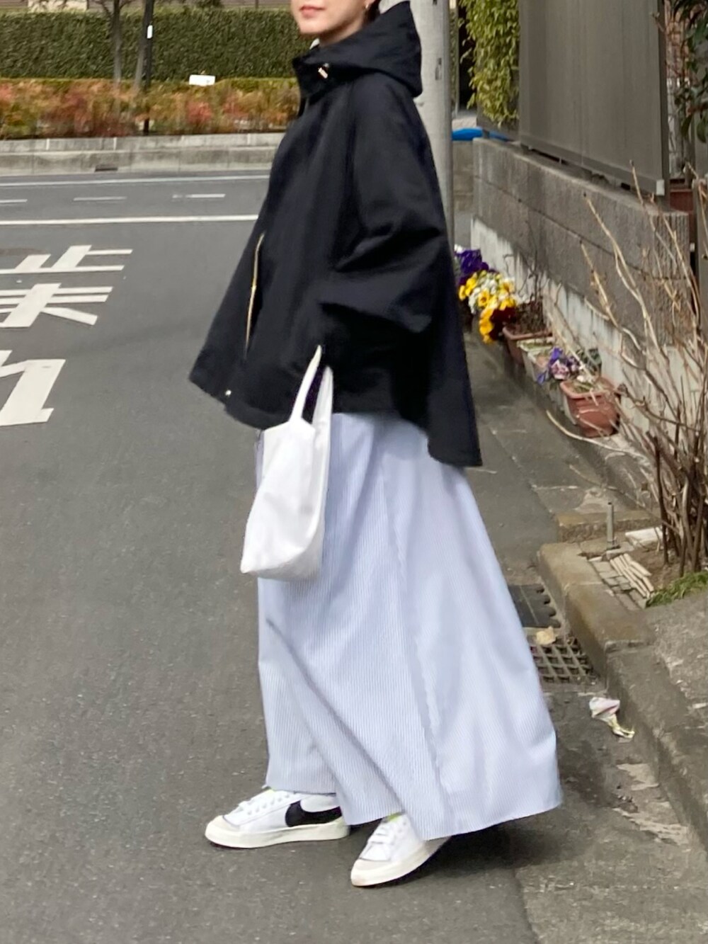 ブラック系のマウンテンパーカー、ブラック系のワンピース、ホワイト系のトートバッグを着用したレディースの冬コーディネートの3枚目の写真