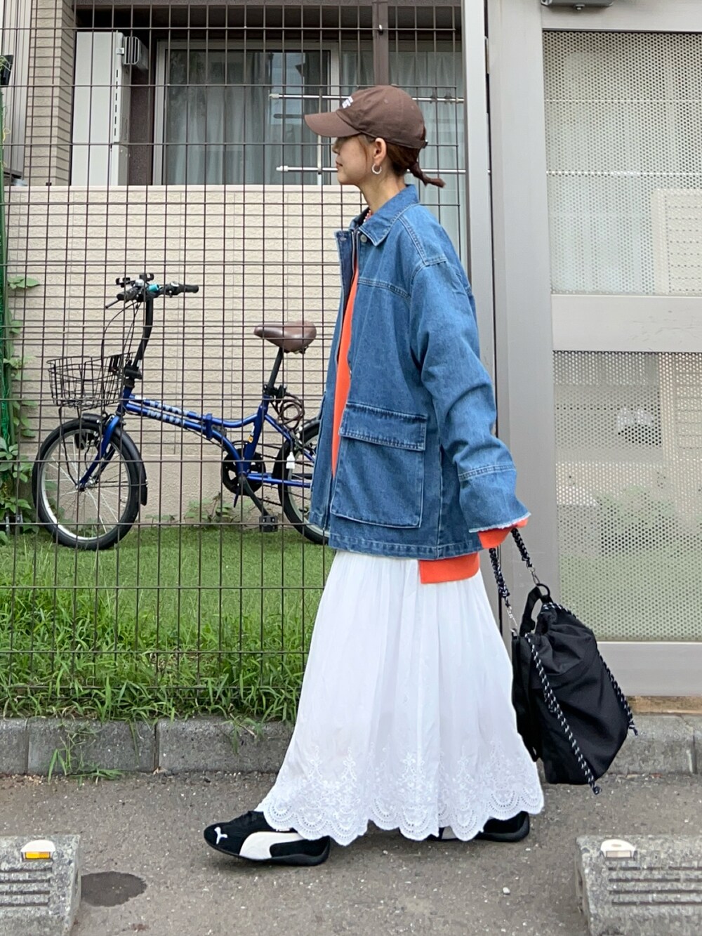 ブルー系のデニムジャケット、オレンジ系のスウェット、ブラック系のショルダーバッグを着用したレディースの秋コーディネートの4枚目の写真