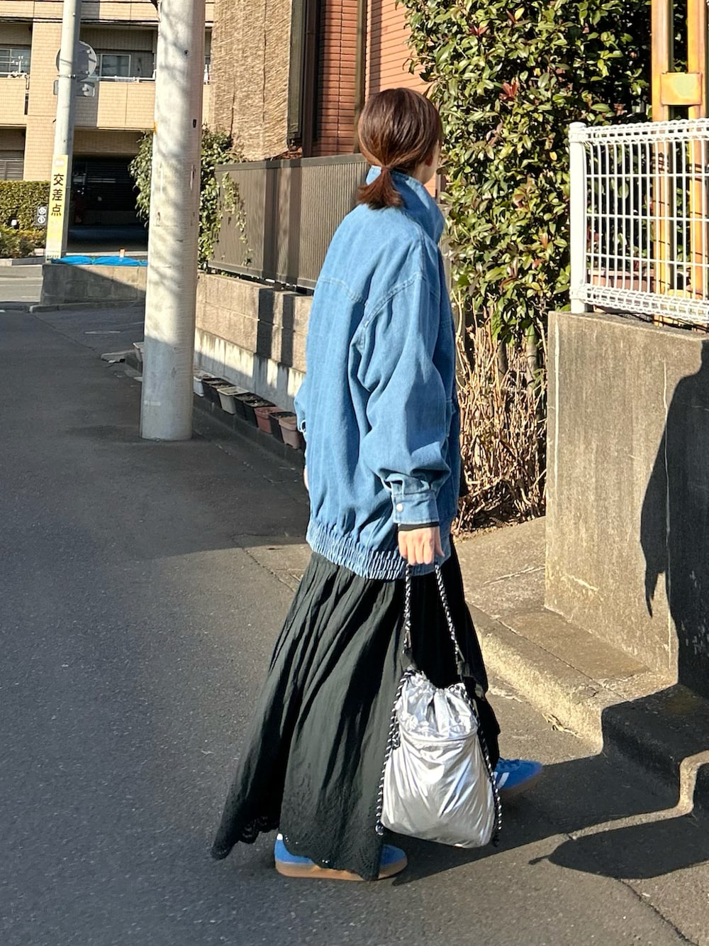 ブルー系のデニムジャケット、ブラック系のスカート、シルバー系のショルダーバッグを着用したレディースの春コーディネートの3枚目の写真