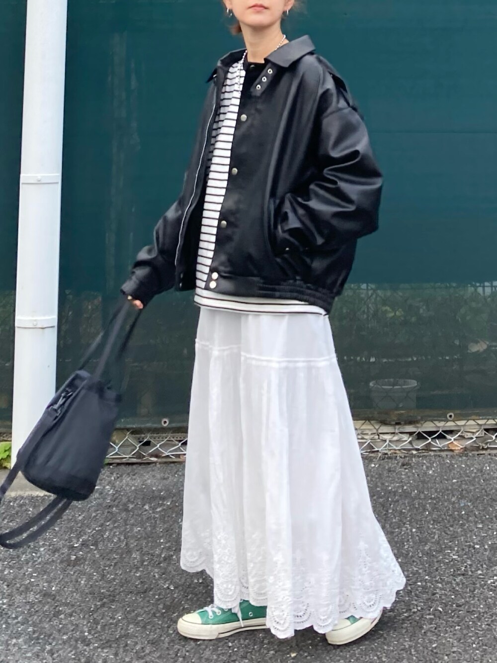 ブラック系のブルゾン、ブラック系のTシャツ/カットソー、ホワイト系のスカートを着用したレディースの春コーディネートの3枚目の写真