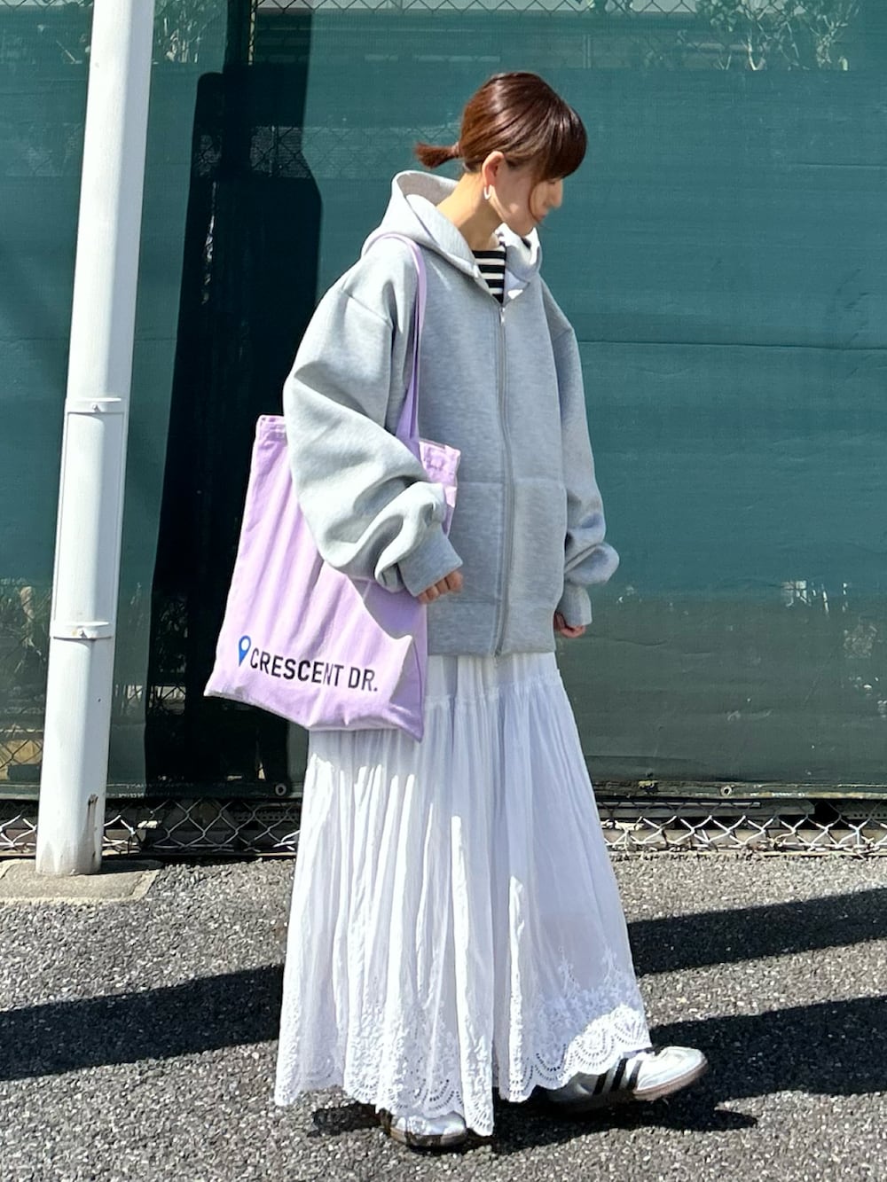 グレー系のパーカー、ホワイト系のスカート、パープル系のトートバッグを着用したレディースの秋コーディネートの3枚目の写真