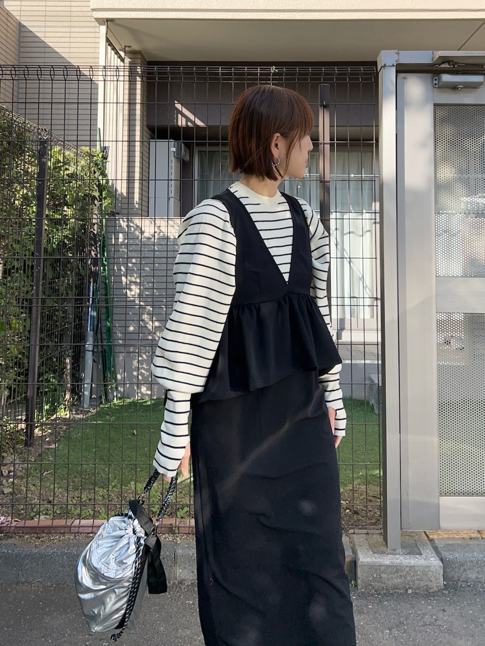 ブラック系のジャンパースカート、ホワイト系のニット/セーター、シルバー系のトートバッグを着用したレディースの冬コーディネートの4枚目の写真