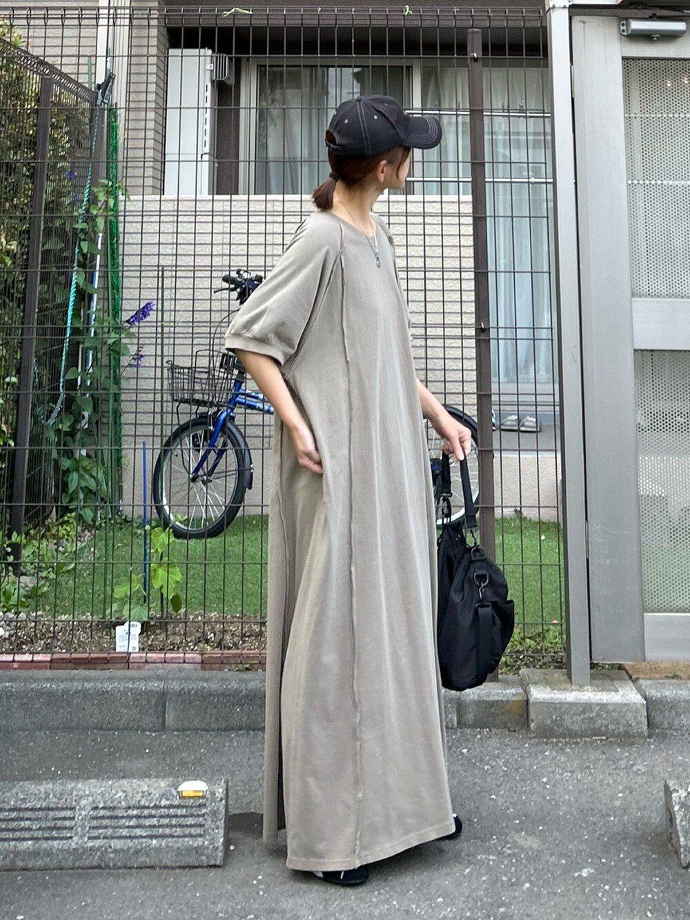 グリーン系のワンピース、ブラック系のショルダーバッグ、ブラック系のスニーカーを着用したレディースの春コーディネートの3枚目の写真