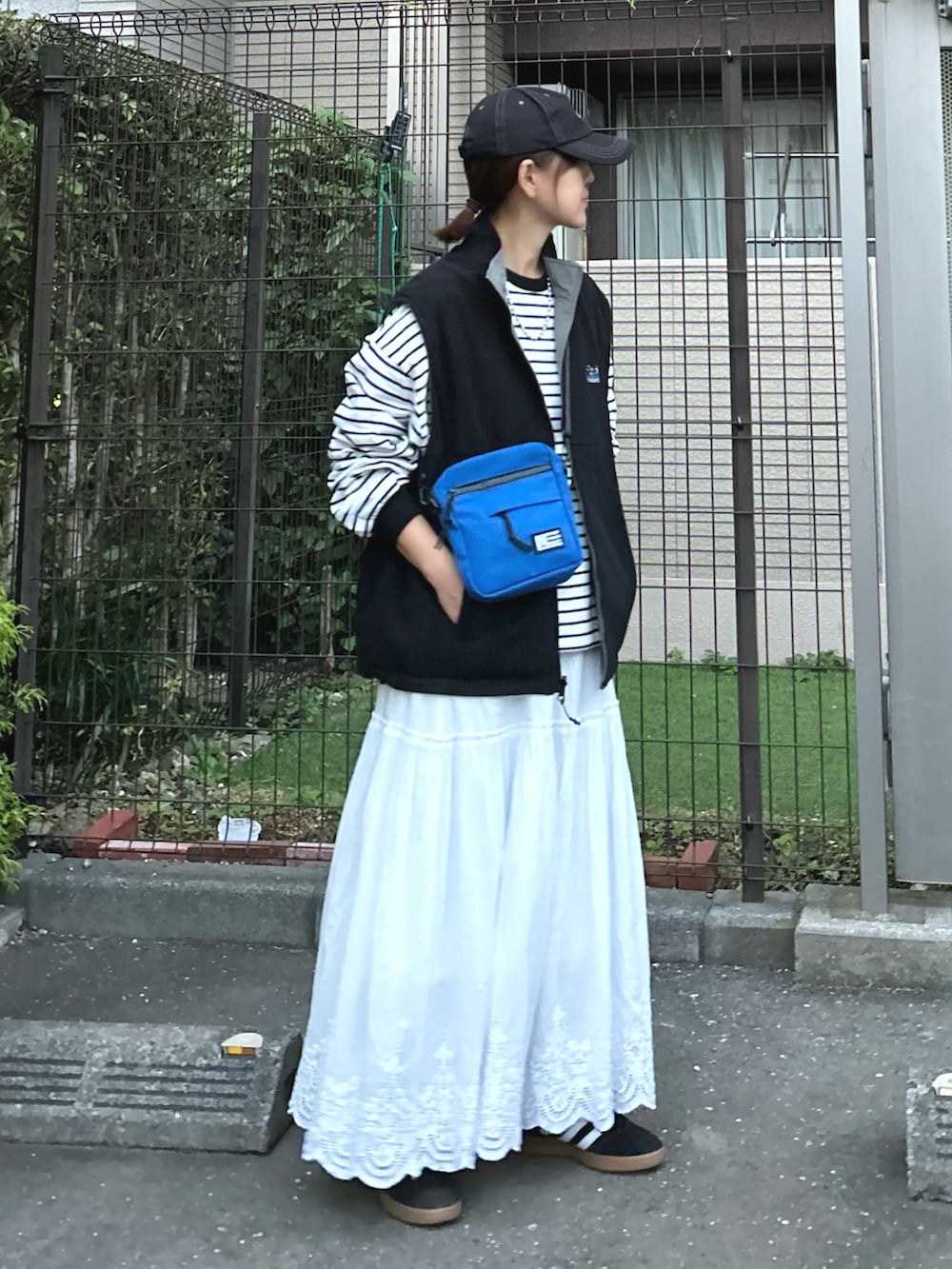 ブラック系のベスト、ブルー系のショルダーバッグ、ブラック系のTシャツ/カットソーを着用したレディースの秋コーディネートの3枚目の写真