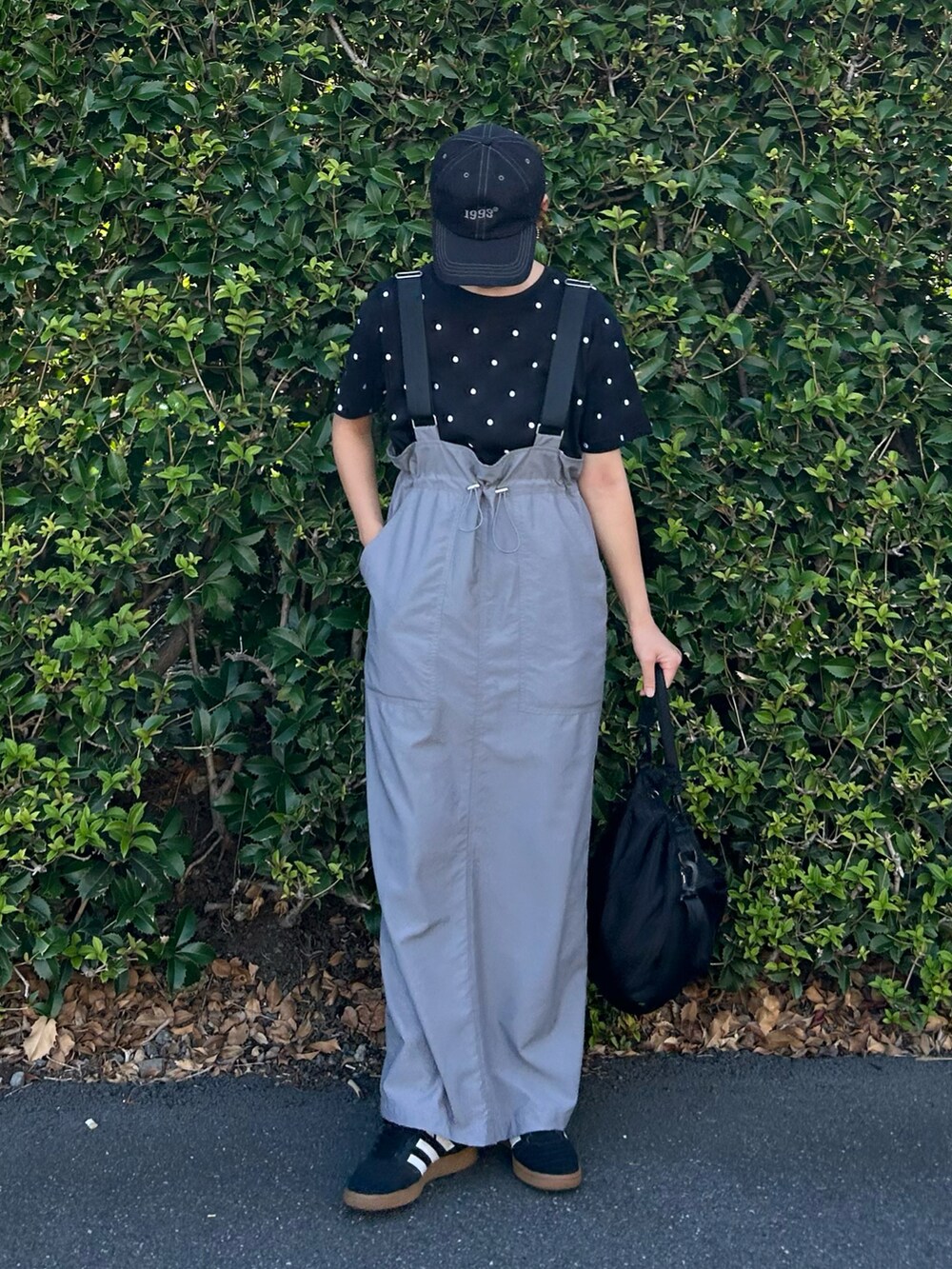 ブラック系のTシャツ/カットソー、グレー系のジャンパースカート、ブラック系のショルダーバッグを着用したレディースの夏コーディネートの2枚目の写真