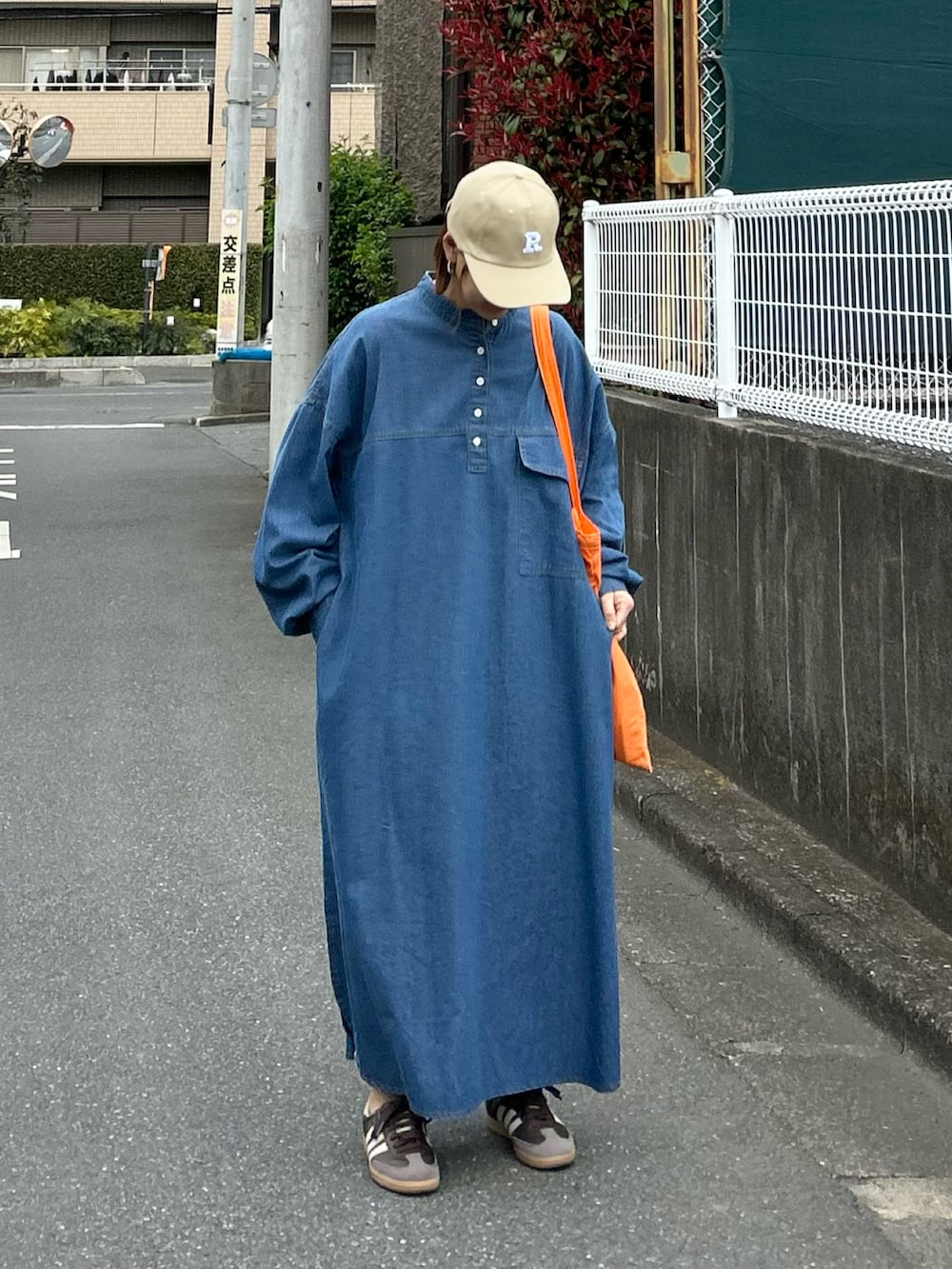 ブルー系のワンピース、ブラウン系のスニーカー、オレンジ系のトートバッグを着用したレディースの春コーディネートの3枚目の写真
