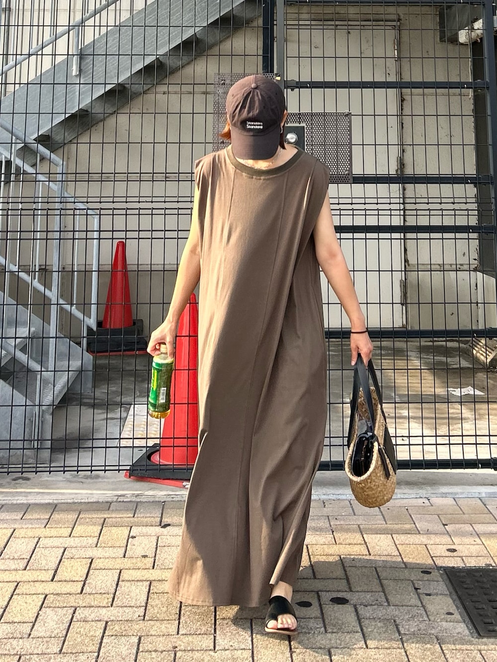 グリーン系のワンピース、ブラック系のかごバッグ、ブラック系のサンダルを着用したレディースの夏コーディネートの2枚目の写真