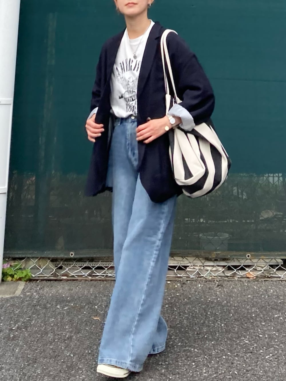 ホワイト系のTシャツ/カットソー、ブルー系のデニムパンツ、ブラック系のトートバッグを着用したレディースの春コーディネートの5枚目の写真