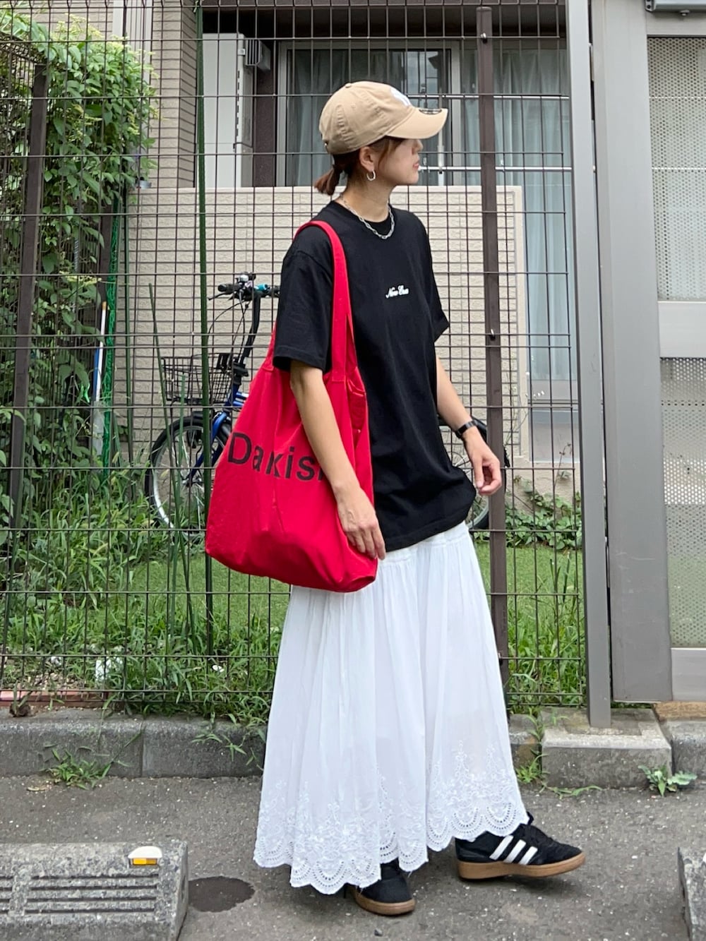 ブラック系のTシャツ/カットソー、レッド系のトートバッグ、ホワイト系のスカートを着用したレディースの夏コーディネートの2枚目の写真