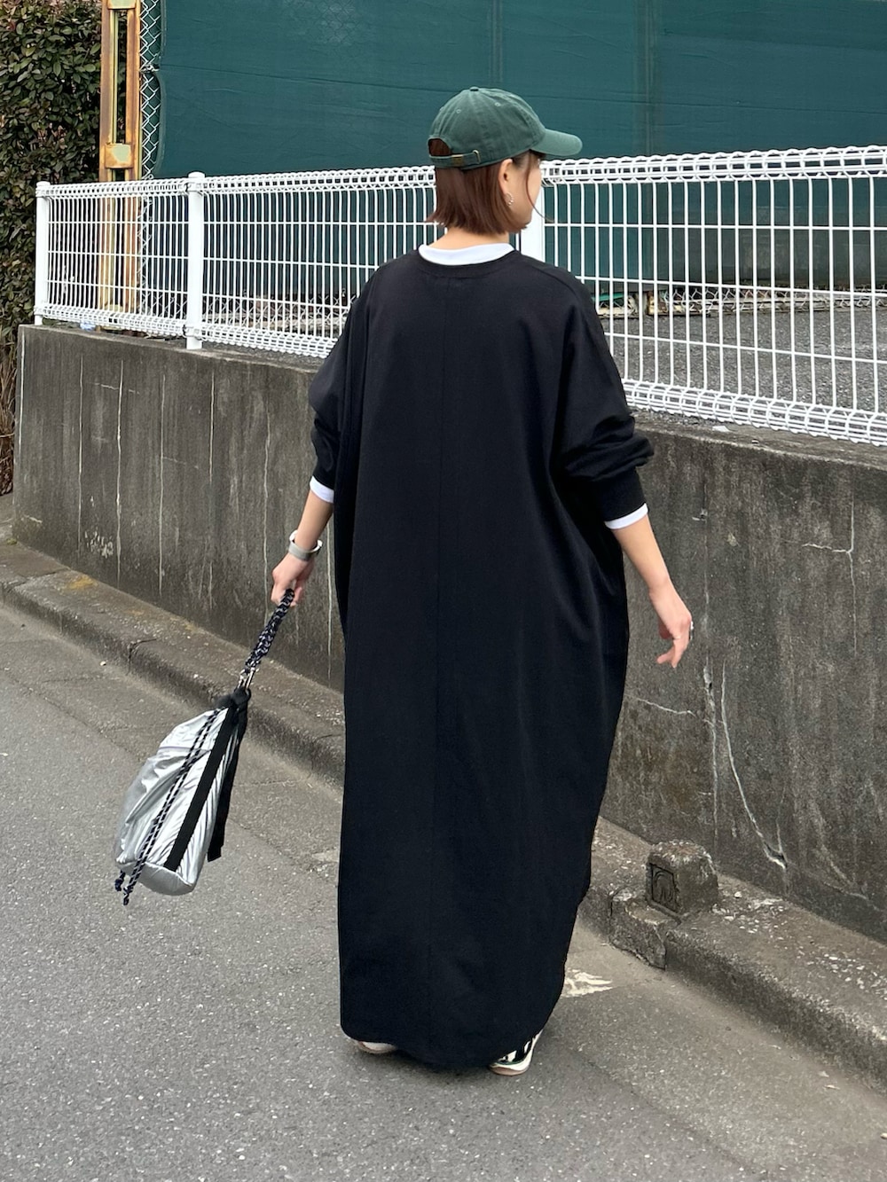 ブラック系のワンピース、シルバー系のトートバッグ、ブラック系のスニーカーを着用したレディースの冬コーディネートの5枚目の写真