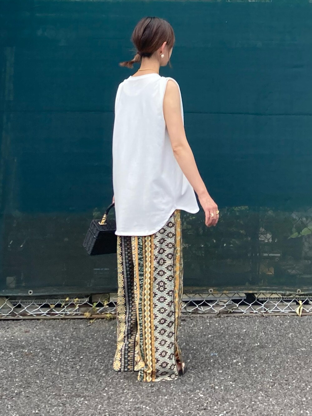 ホワイト系のタンクトップ、イエロー系のその他パンツ、ブラック系のかごバッグを着用したレディースの夏コーディネートの4枚目の写真