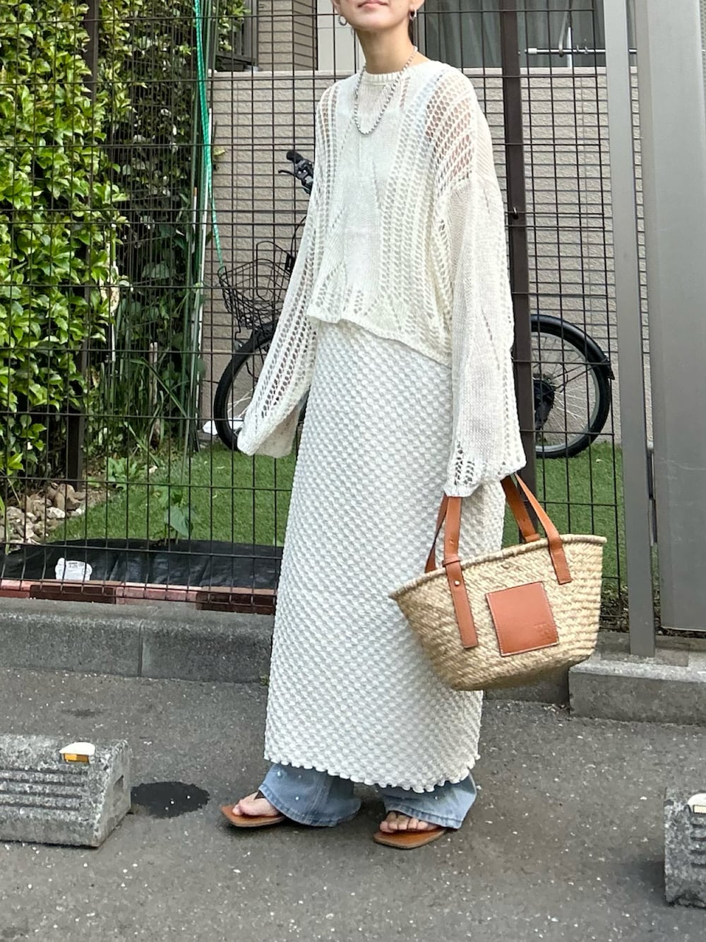 ホワイト系のワンピース、ブラウン系のかごバッグ、ブルー系のデニムパンツを着用したレディースの春コーディネートの4枚目の写真