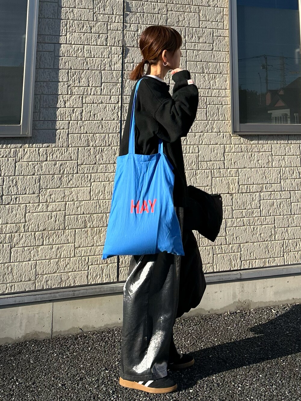 ブラック系のニット/セーター、ブラック系のその他パンツ、ブルー系のトートバッグを着用したレディースの春コーディネートの3枚目の写真