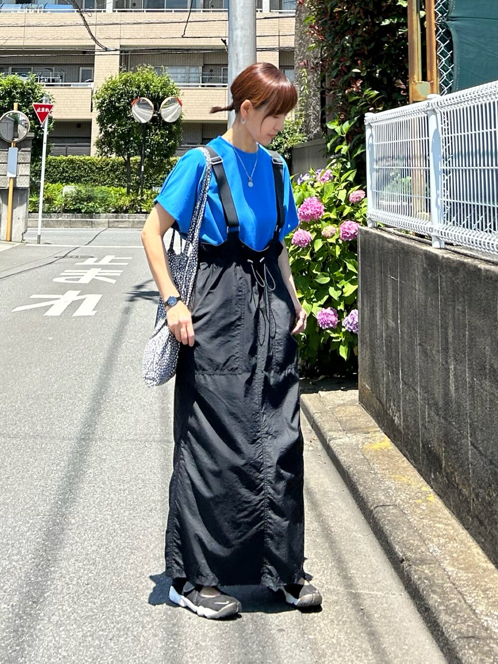 ブルー系のTシャツ/カットソー、ブラック系のジャンパースカート、ブラック系のスニーカーを着用したレディースの夏コーディネートの2枚目の写真