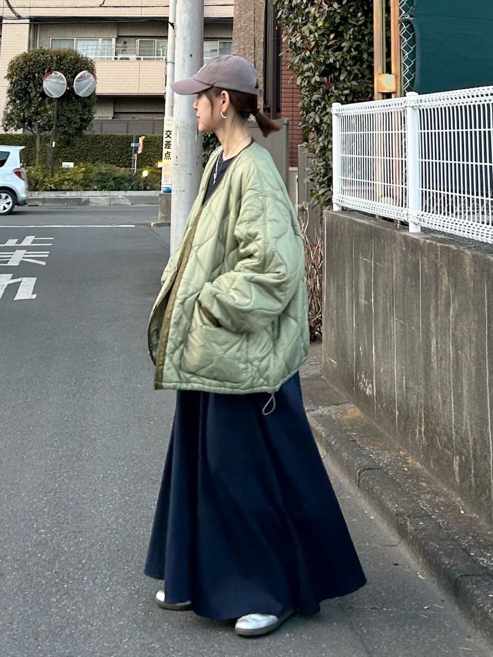 ブルー系のワンピース、グリーン系のノーカラージャケット、シルバー系のスニーカーを着用したレディースの冬コーディネートの3枚目の写真