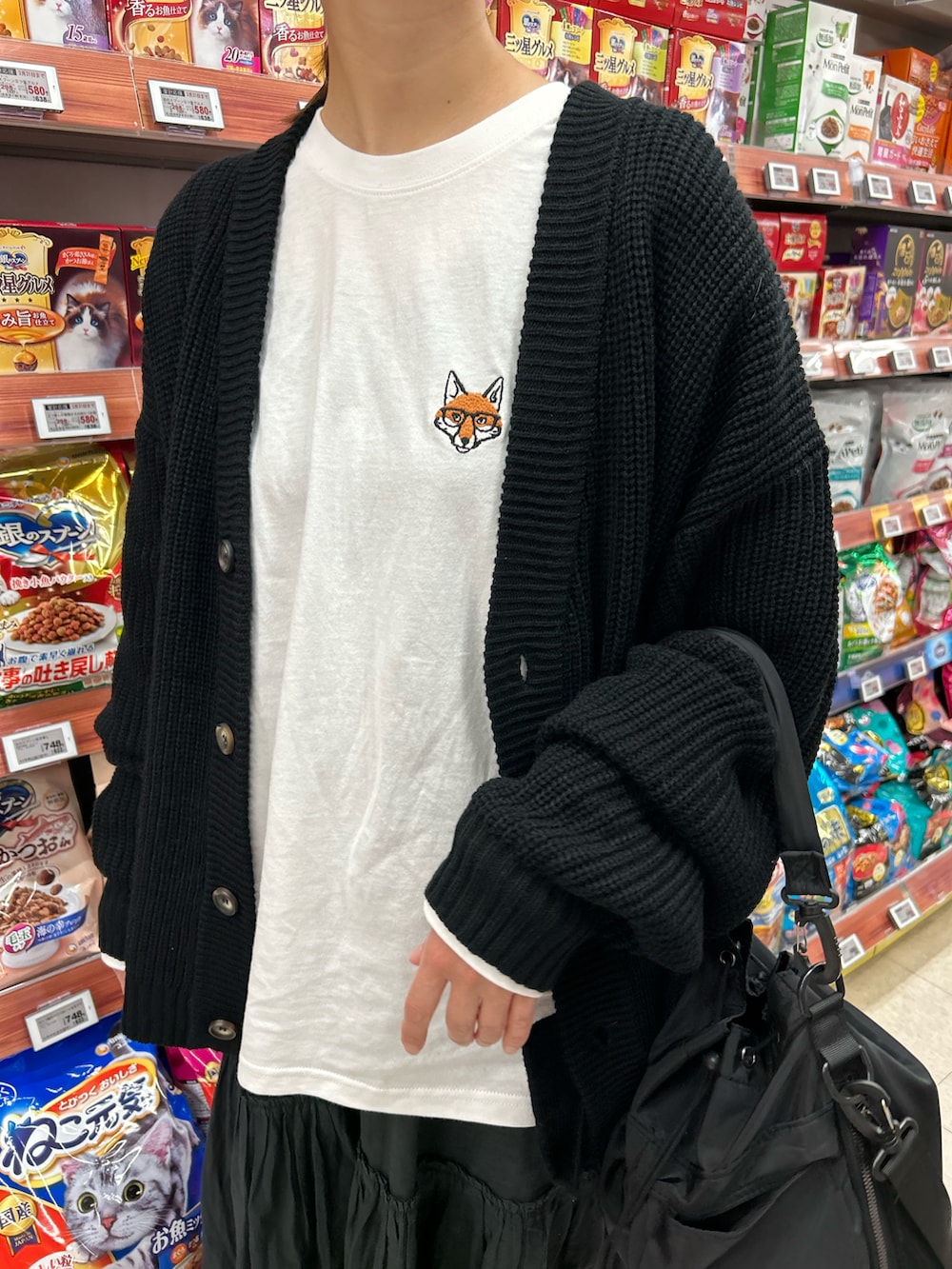 ホワイト系のTシャツ/カットソー、ブラック系のカーディガン/ボレロ、ブラック系のスカートを着用したレディースの春コーディネートの5枚目の写真