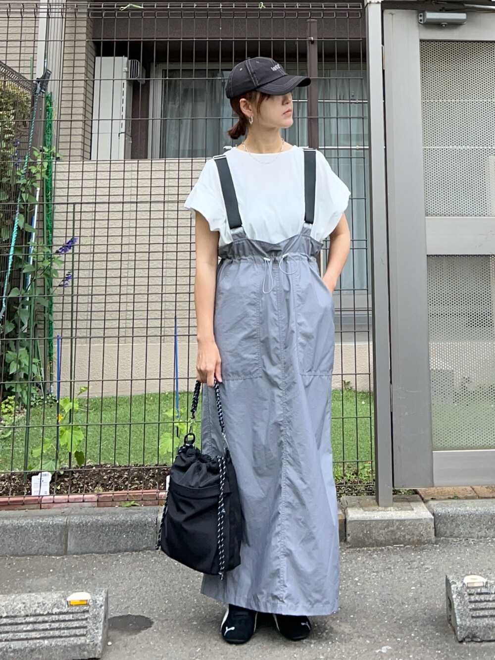 グレー系のジャンパースカート、ブラック系のトートバッグ、ブラック系のスニーカーを着用したレディースの夏コーディネートの4枚目の写真