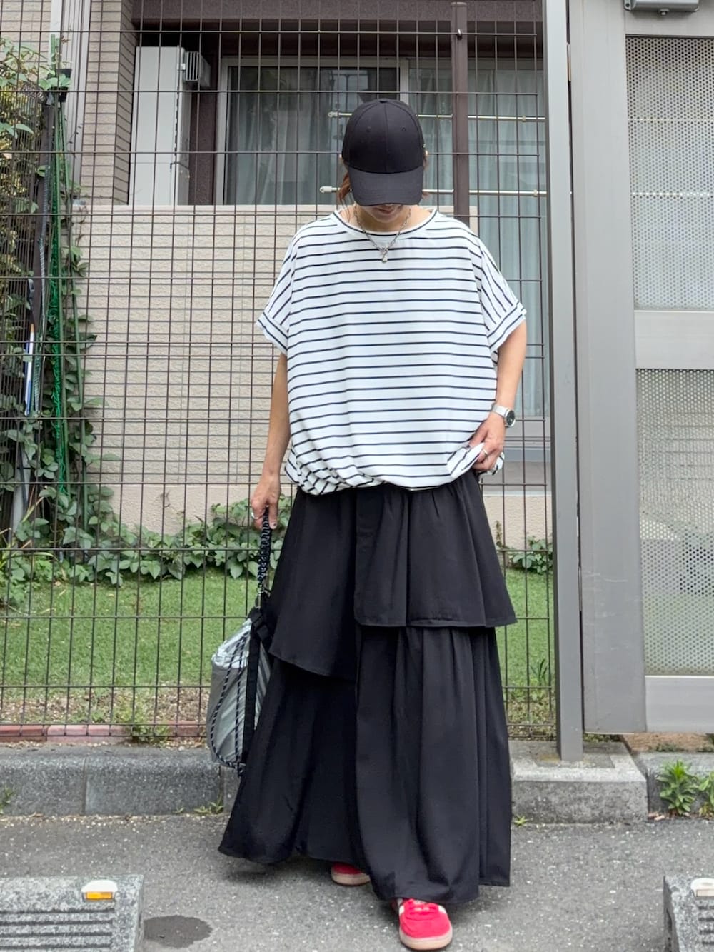 ブラック系のスカート、シルバー系のショルダーバッグ、ホワイト系のTシャツ/カットソーを着用したレディースの春コーディネートの4枚目の写真
