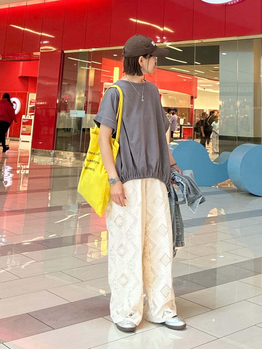 グレー系のTシャツ/カットソー、ホワイト系のスラックス、シルバー系のスニーカーを着用したレディースの春コーディネートの2枚目の写真