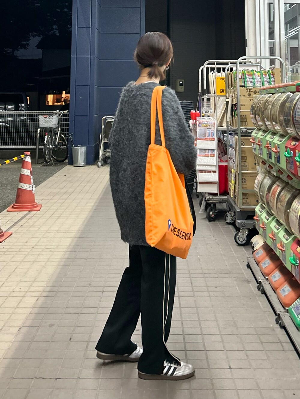 ブラック系のスウェットパンツ、オレンジ系のトートバッグ、グレー系のカーディガン/ボレロを着用したレディースの秋コーディネートの2枚目の写真