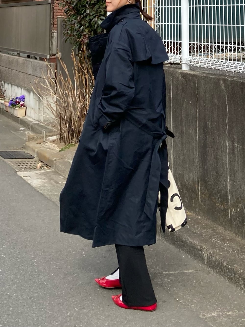 ブルー系のトレンチコート、ブラック系のTシャツ/カットソー、ホワイト系のトートバッグを着用したレディースの冬コーディネートの5枚目の写真