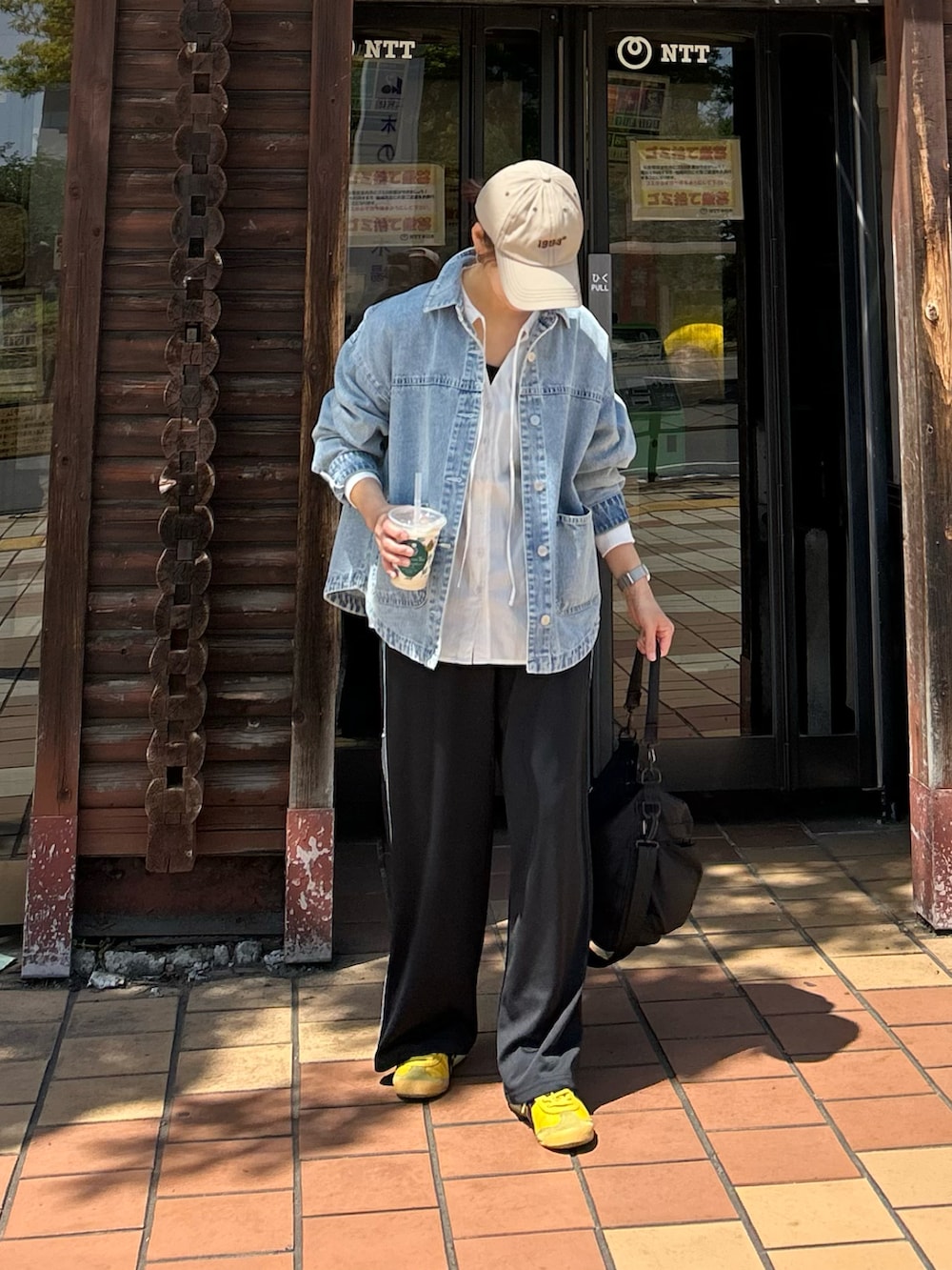 ブルー系のデニムジャケット、ホワイト系のシャツ/ブラウス、ブラック系のスラックスを着用したレディースの春コーディネートの4枚目の写真