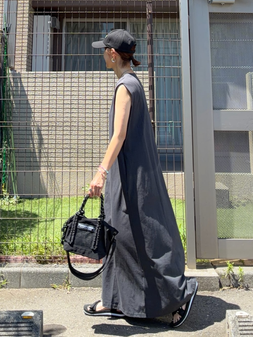 グレー系のワンピース、ブラック系のトートバッグ、ブラック系のキャップを着用したレディースの夏コーディネートの4枚目の写真