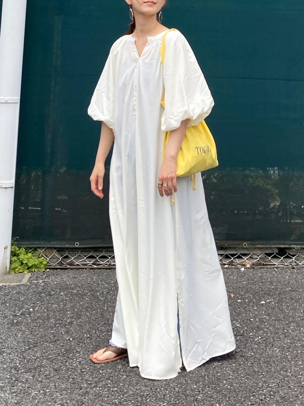 ホワイト系のワンピース、イエロー系のトートバッグ、ブルー系のデニムパンツを着用したレディースの夏コーディネートの4枚目の写真