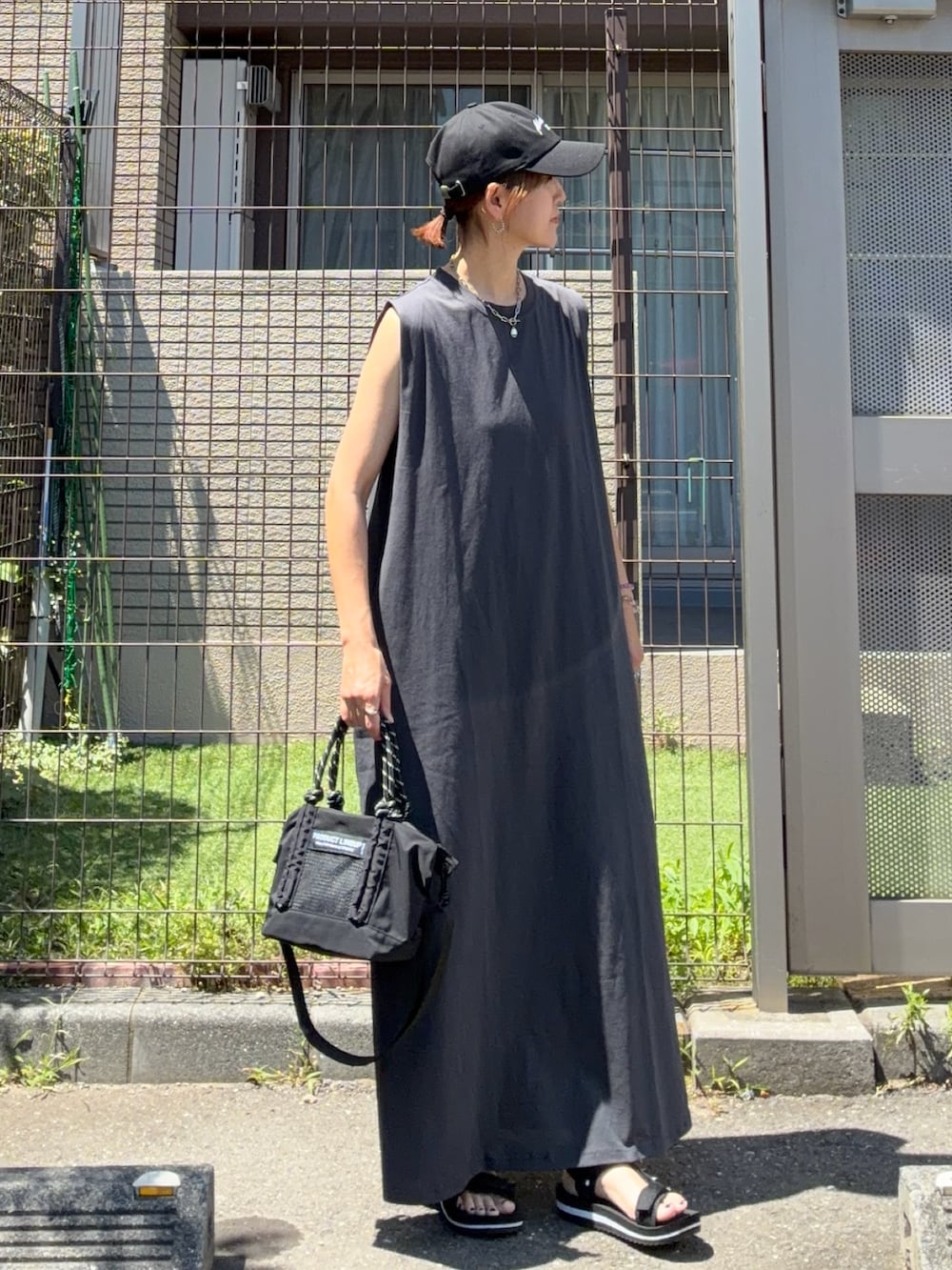 グレー系のワンピース、ブラック系のトートバッグ、ブラック系のキャップを着用したレディースの夏コーディネートの2枚目の写真