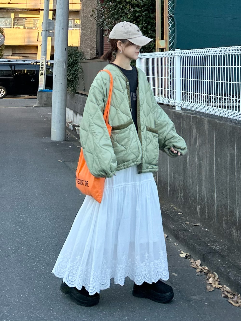 ブラック系のTシャツ/カットソー、グリーン系のノーカラージャケット、ホワイト系のスカートを着用したレディースの冬コーディネートの5枚目の写真