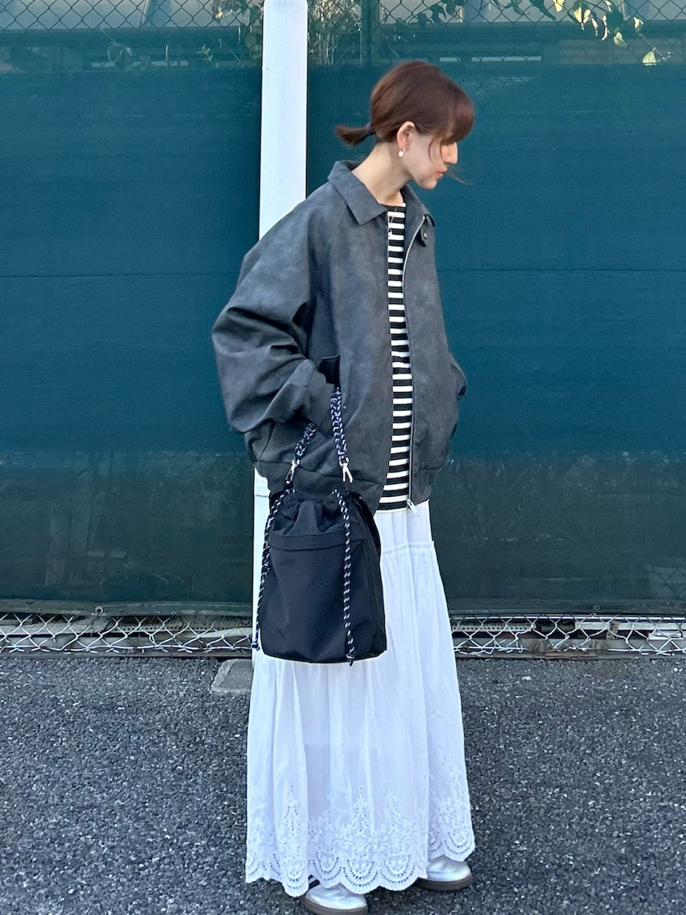 ブラック系のブルゾン、ブラック系のトートバッグ、ホワイト系のスカートを着用したレディースの秋コーディネートの4枚目の写真
