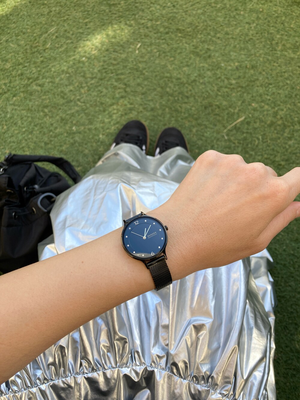 ブラック系のダウンベスト、シルバー系のスカート、ブラック系のパーカーを着用したレディースの冬コーディネートの2枚目の写真