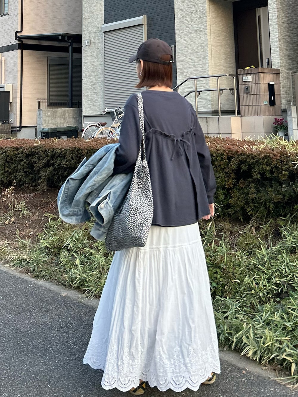 ホワイト系のスカート、グレー系のアンサンブル、イエロー系のスニーカーを着用したレディースの冬コーディネートの2枚目の写真