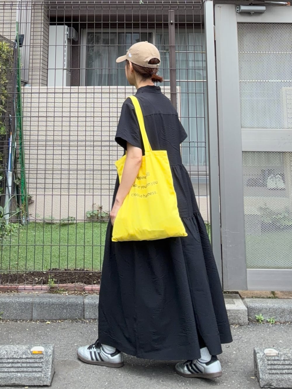 ブラック系のワンピース、イエロー系のトートバッグ、ベージュ系のキャップを着用したレディースの春コーディネートの3枚目の写真
