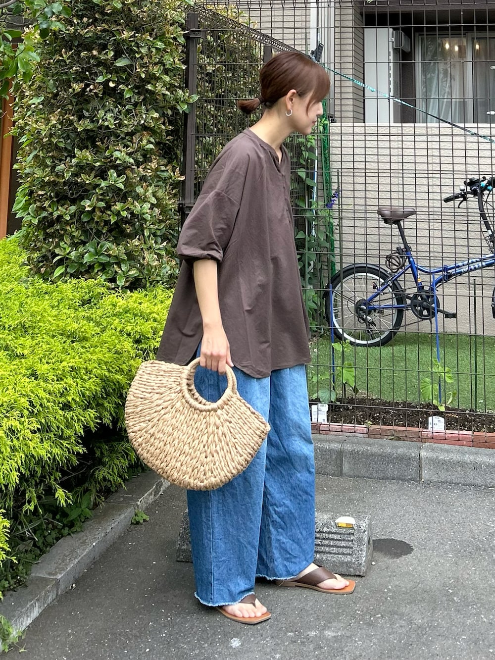 ブラウン系のTシャツ/カットソー、ブルー系のデニムパンツ、ベージュ系のかごバッグを着用したレディースの春コーディネートの3枚目の写真