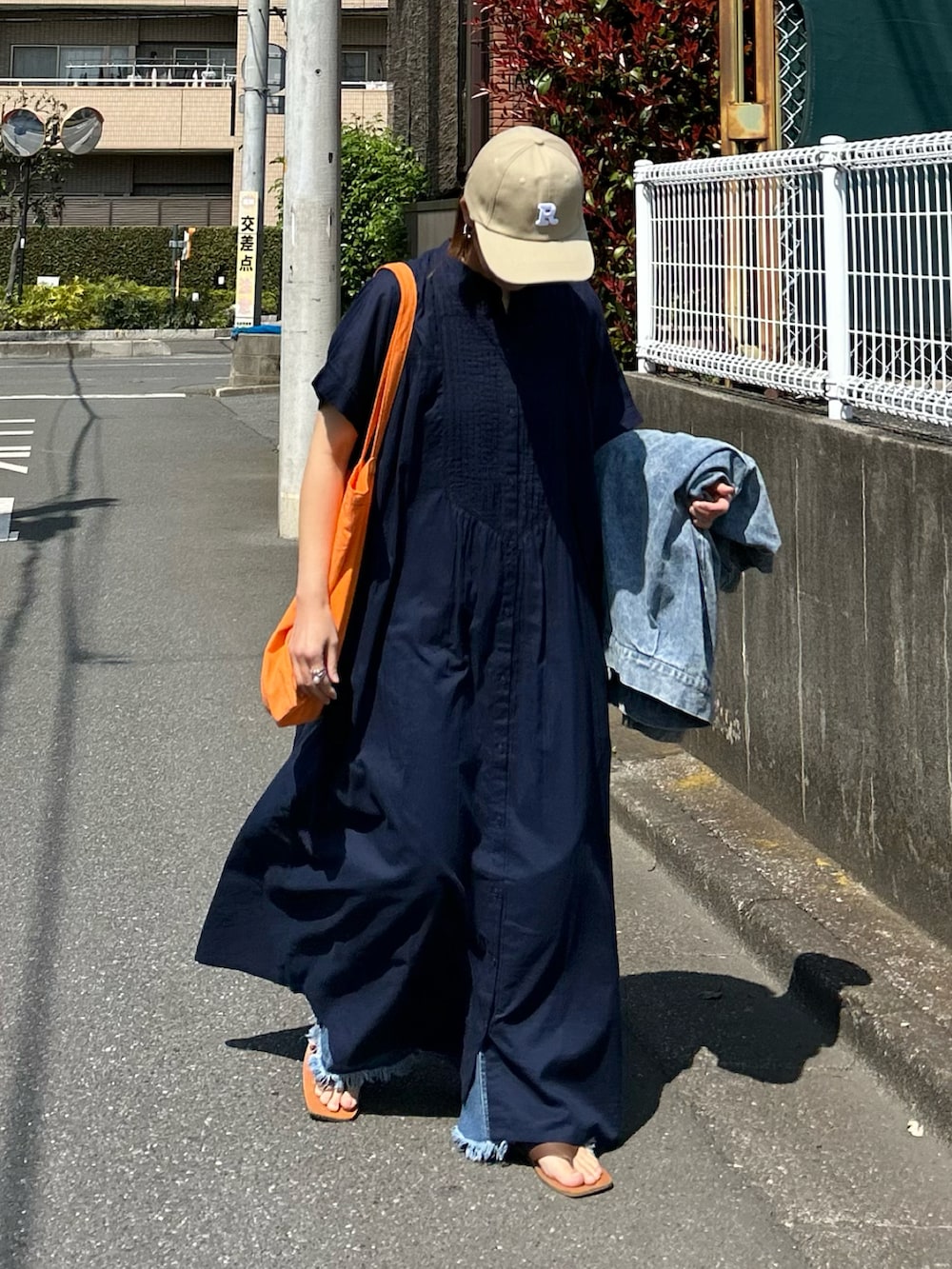 ブルー系のワンピース、オレンジ系のトートバッグ、ベージュ系のキャップを着用したレディースの夏コーディネートの4枚目の写真