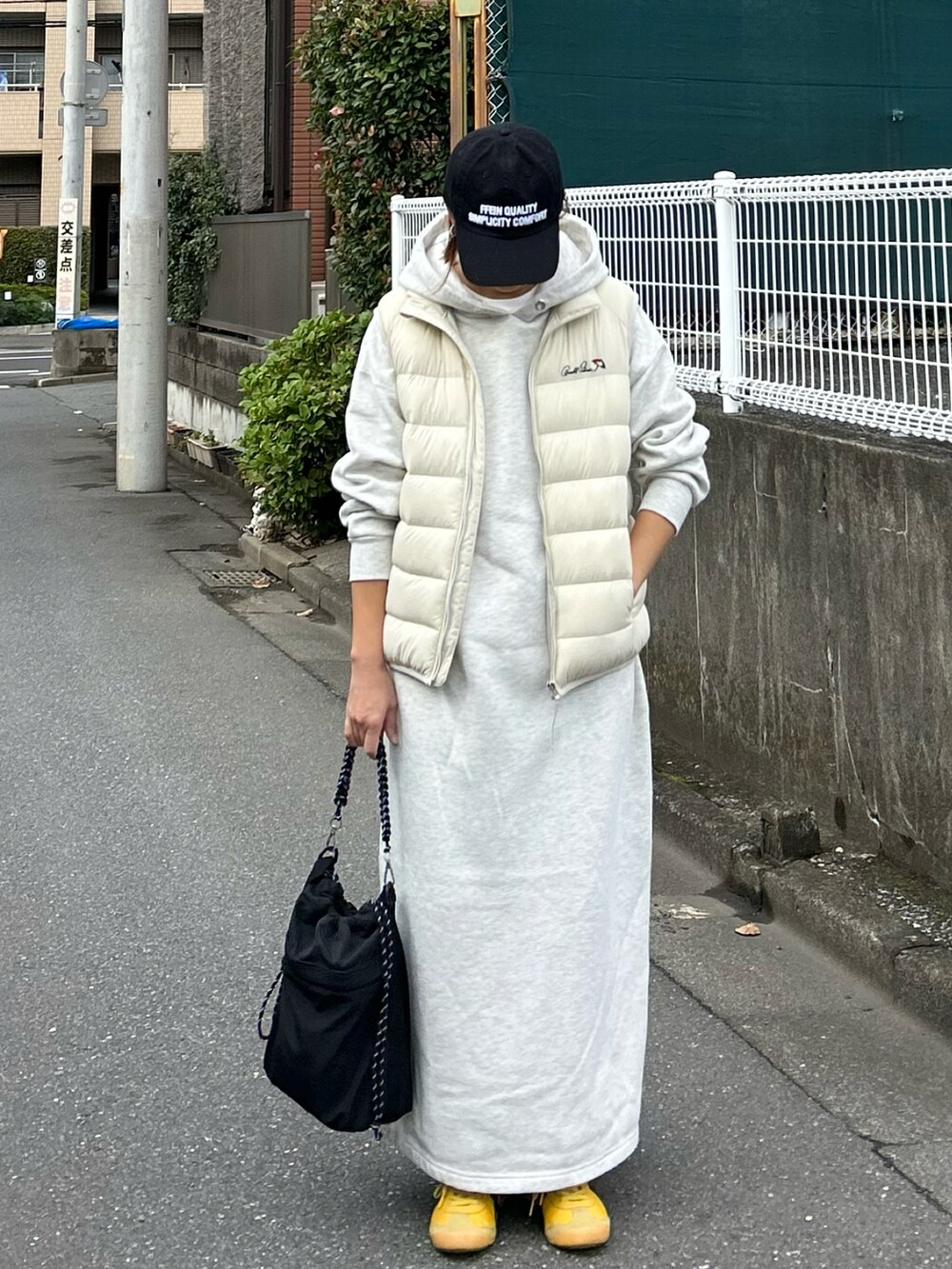 ホワイト系のダウンベスト、ブラック系のショルダーバッグ、グレー系のワンピースを着用したレディースの秋コーディネートの3枚目の写真
