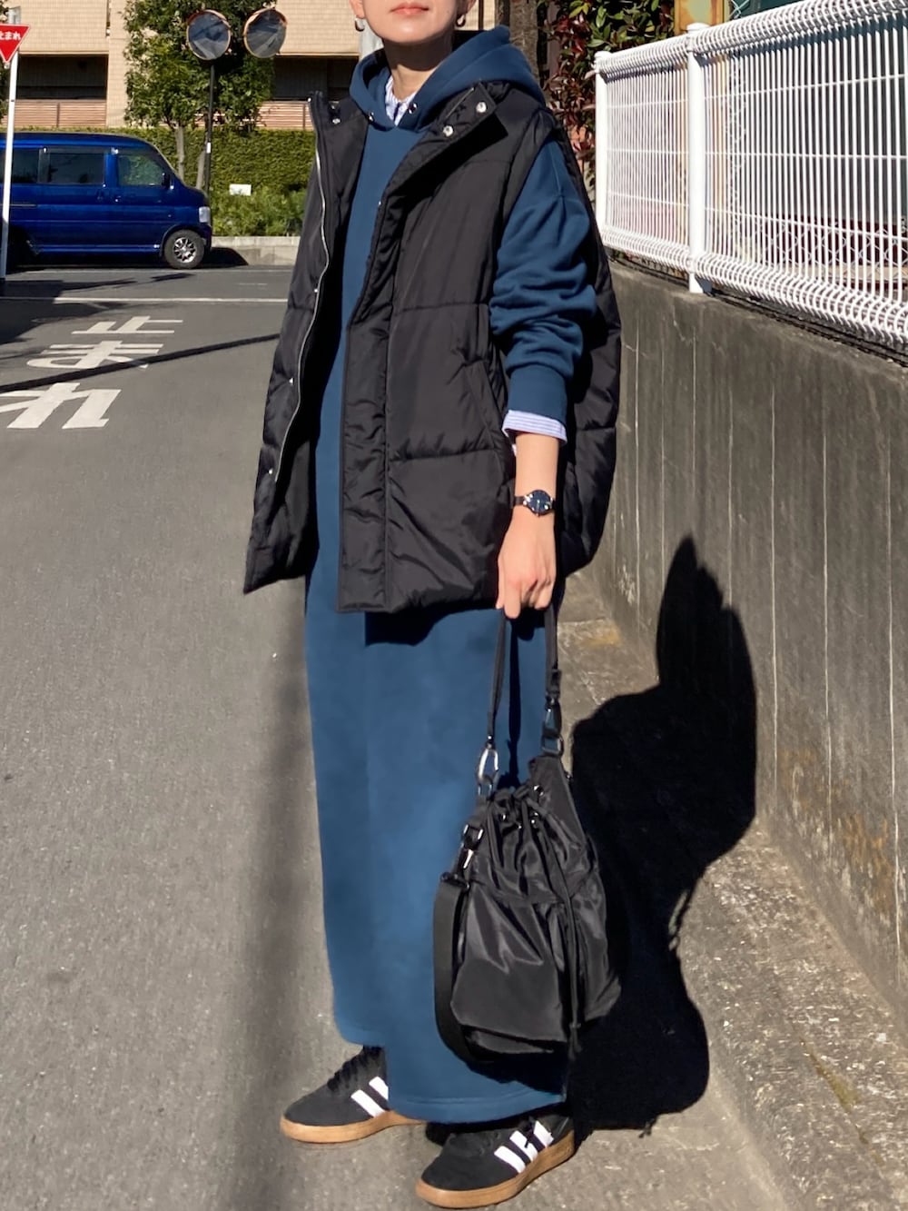 ブラック系のダウンベスト、ブルー系のワンピース、ブラック系のショルダーバッグを着用したレディースの冬コーディネートの2枚目の写真