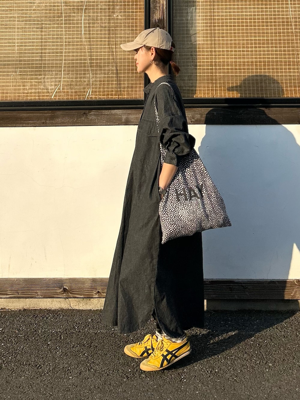 ブラック系のワンピース、イエロー系のスニーカー、ベージュ系のキャップを着用したレディースの春コーディネートの4枚目の写真