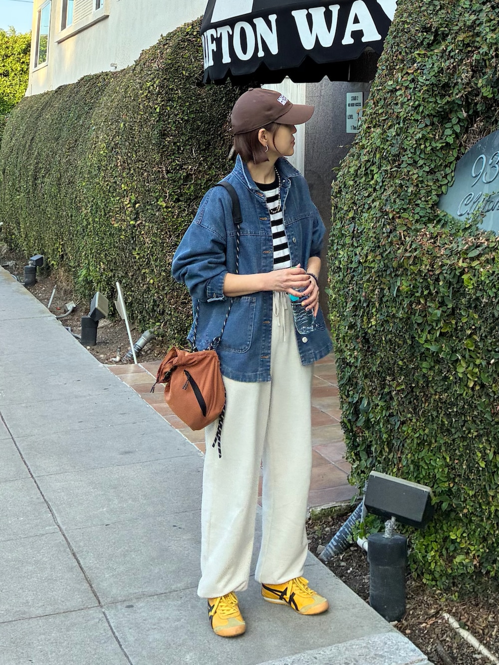 ブラック系のTシャツ/カットソー、オレンジ系のショルダーバッグ、ブルー系のデニムジャケットを着用したレディースの春コーディネートの3枚目の写真